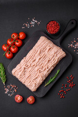 Fresh minced chicken with salt, spices and herbs on a wooden cutting board