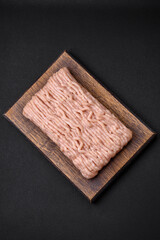 Fresh minced chicken with salt, spices and herbs on a wooden cutting board