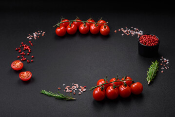 Empty black texture table, cherry tomatoes on a twig, spices, salt and herbs