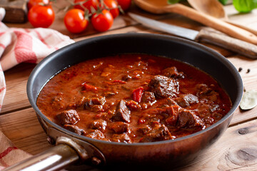 Traditional Czech Goulash meal in a frying pan on table, beer Guláš