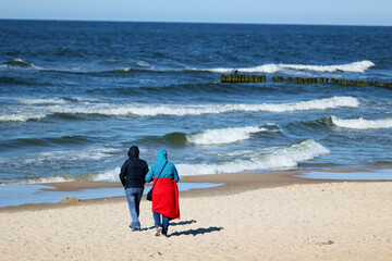 Ciepło ubrani ludzie na plaży nad morzem wiosną. 