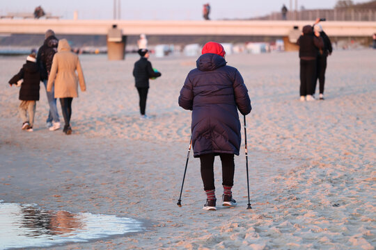 Ciepło ubrani ludzie na plaży nad morzem wiosną. 