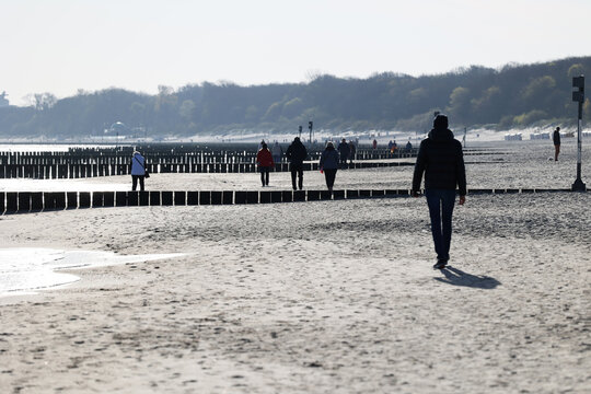 Ciepło ubrani ludzie na plaży nad morzem wiosną. 