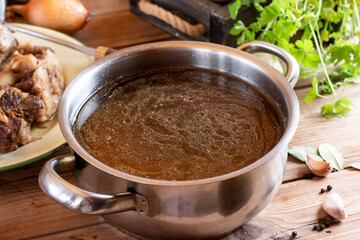 Beef Bone Broth in a glass jar, with fresh vegetables on wooden table