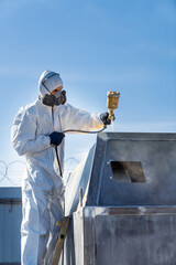 Man painting in suit. Worker in white suit finishing with paint.