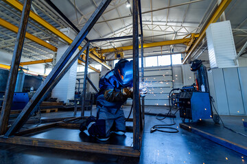 Worker in helmet welding. Industrial welder on workplace.