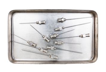 vintage steel hypodermic needles in steel syringe boil container isolated on white background