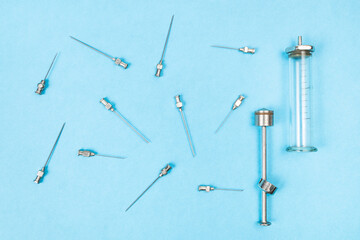 top view of vintage steel hypodermic needles and glass syringe on blue paper background
