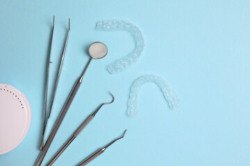 Transparent plastic aligners and dentist's tools on a colored background