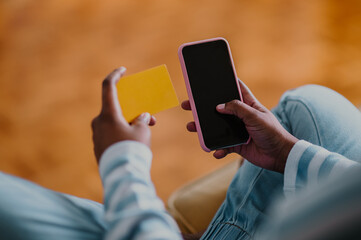 African american woman using credit card and asmartphone while online shopping at home