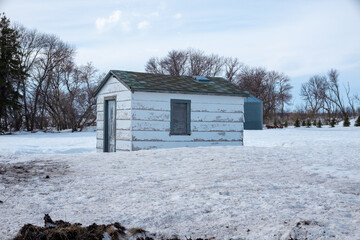 dilapidated building on farmstead in north dakota in winter with blue skies