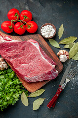 top view raw meat sliced with red tomatoes and greens on a dark background color food meat barbecue cooking meal butcher