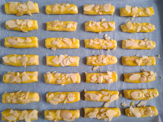 Rectangular shape of Cookies dough with almond slices topping placed in a baking sheet ready to oven