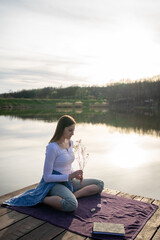 Fototapeta na wymiar Woman relaxing on lakeshore, nature concept, sunset.