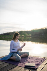 Fototapeta premium Woman relaxing on lakeshore, nature concept, sunset.