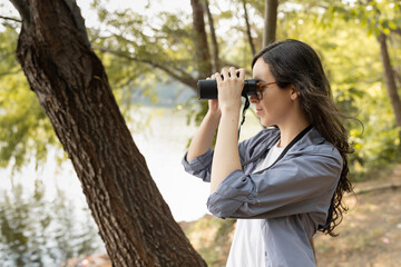 Female Using Binoculars to Watch Birds in a Lagoon