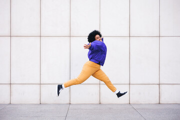 afro woman jumping on white wall, copy space for social media