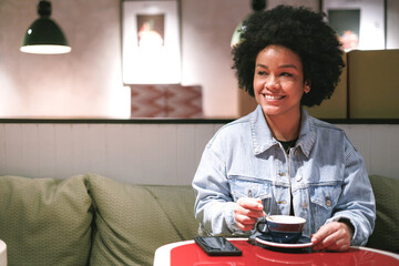 Fototapeta na wymiar afro woman drinking coffee in a cafe, close up view