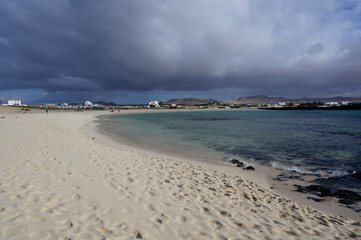 White sand, blue water and stormy clouds on La Concha beach, El Cotillo surfers village, Fuerteventura, Canary islands, Spain