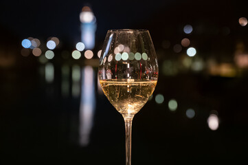 Tasting of french sparkling white wine with bubbles champagne outdoor at night with view on Marne river and lights of Epernay city in winter