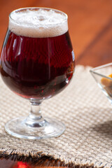 Glass of Belgian abbey red brown beer and glass bowl with party nuts
