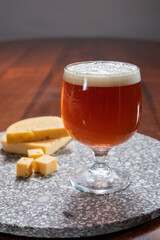 Glass of Belgian light blond beer made in abbey and tasty belgian cheese