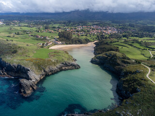 Aerial view on Playa de Poo during low tide near Llanes, Green coast of Asturias, North Spain with sandy beaches, cliffs, hidden caves, green fields and mountains.