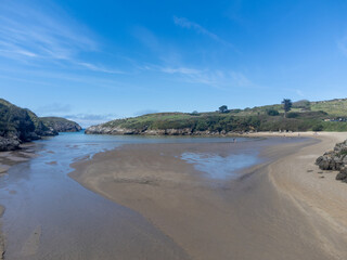 Aerial view on Playa de Poo during low tide near Llanes, Green coast of Asturias, North Spain with sandy beaches, cliffs, hidden caves, green fields and mountains.