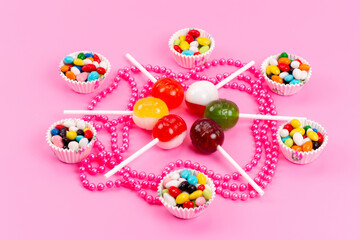 a front view colorful candies along with lollipops isolated on the pink background sweet sugar color