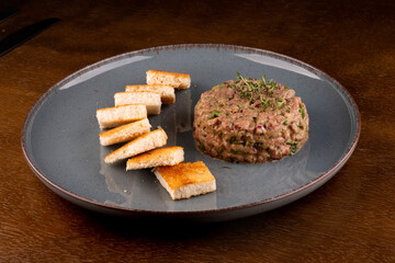 portion of raw meat tartar with spices close-up with toast