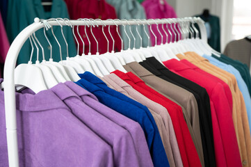 Obraz premium Women's dresses on hangers in a retail shop. Row of different female clothes hanging on rack in fashion show room