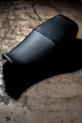 Sella sellino di una motocicletta in pelle nera su un tavolo di legno di un tappezziere, prodotto nuovo appena confezionato - obrazy, fototapety, plakaty