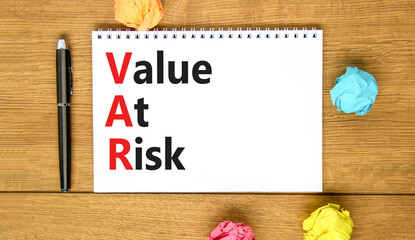 VAR Value at risk symbol. Concept words VAR Value at risk on beautiful white note. Beautiful wooden...