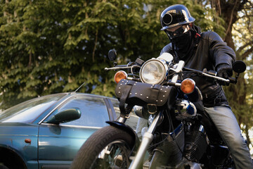 Biker in a helmet and glasses on a chopper motorcycle with a wardrobe trunk