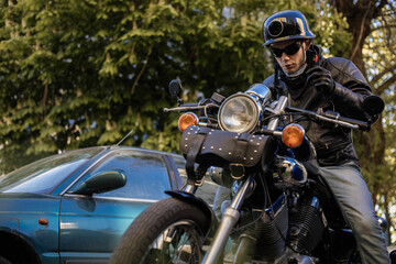 Biker in a helmet and glasses on a chopper motorcycle with a wardrobe trunk