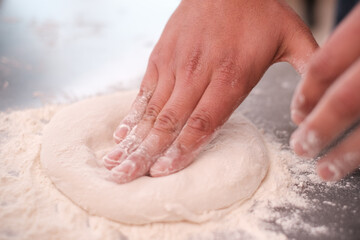 Mani di un fornaio che impastano la pasta del pane con luce naturale su un tavolo di marmo bianco