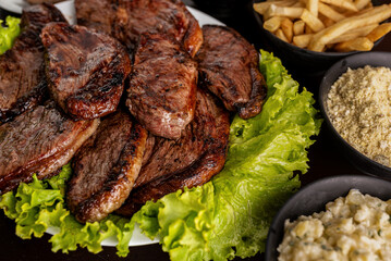 Churrasco - grilled sirloin steak with garnishes - rice, farofa, vinaigrette, potato salad, and fries