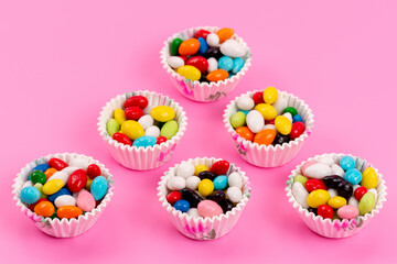 a top view colorful candies inside paper packages on the pink background sweet sugar color