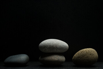 gray zen stones on a dark gray background with shadows for a podium background.a group of oval stones for product presentation