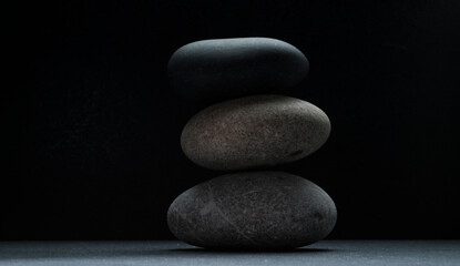 gray zen stones on a dark gray background with shadows for a podium background.a group of oval...