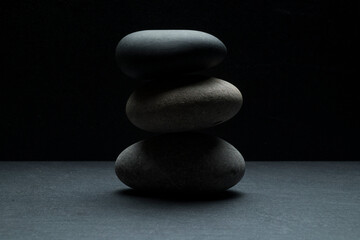 gray zen stones on a dark gray background with shadows for a podium background.a group of oval...