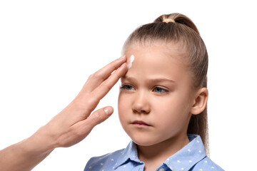 Mother applying ointment on her daughter's forehead against white background