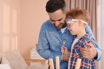 Father and son repairing stool at home, space for text