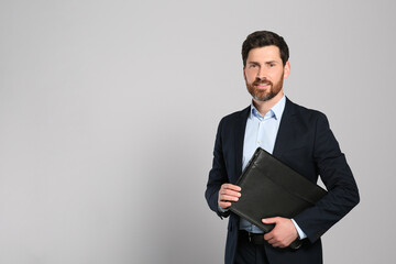 Handsome real estate agent with documents on grey background, space for text