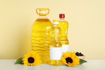 Bottles of cooking oil, sunflowers and seeds on white table