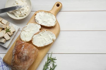 Gordijnen Slices of baguette with tofu cream cheese and rosemary on white wooden table, flat lay. Space for text © New Africa