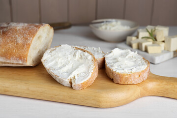 Slices of baguette with tofu cream cheese on white wooden table
