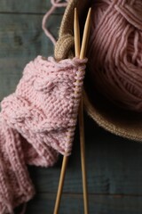 Soft pink woolen yarn, knitting and needles on wooden table, top view