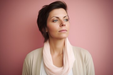 Fototapeta premium Portrait of a young woman with pink scarf over pink background.