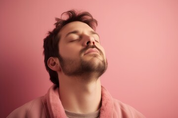 Fototapeta premium Young man in a pink hoodie sleeping on a pink background.